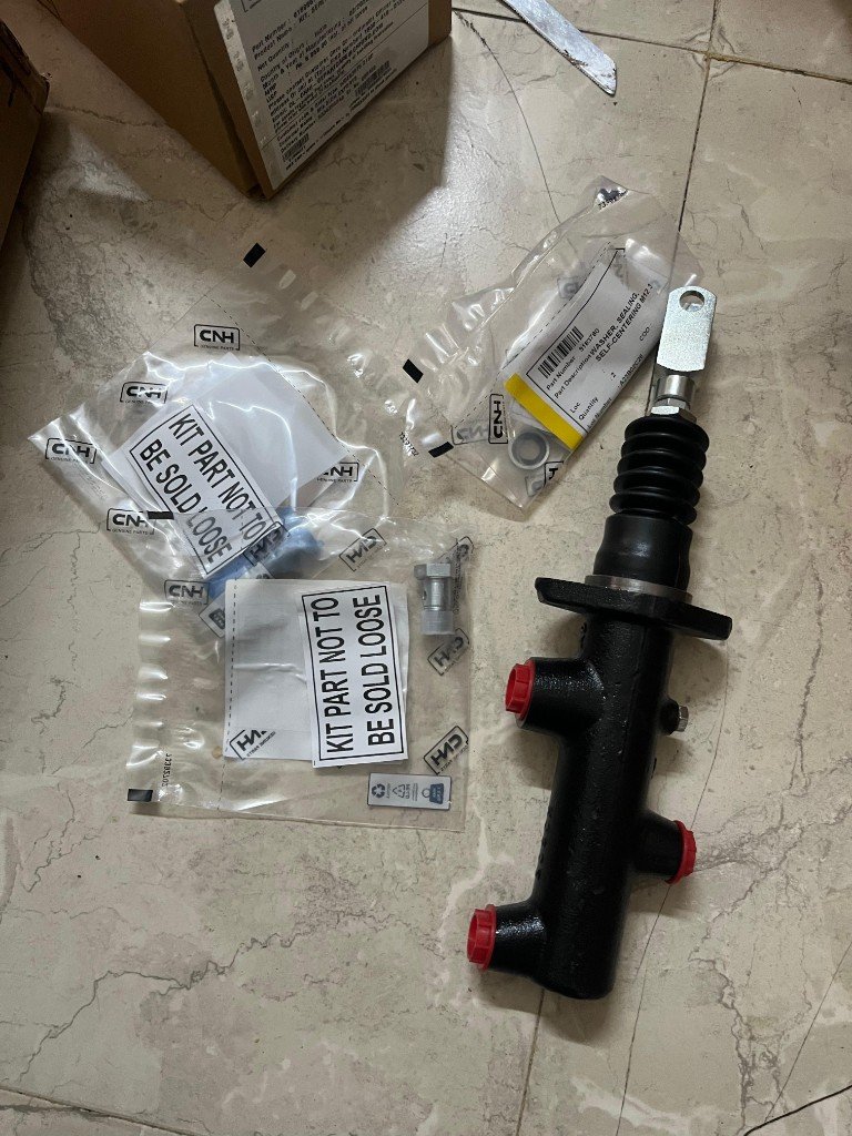 Case CNH 91896671 master brake cylinder with CNH Genuine Parts retail packaging wide view — multi-angle warehouse photo