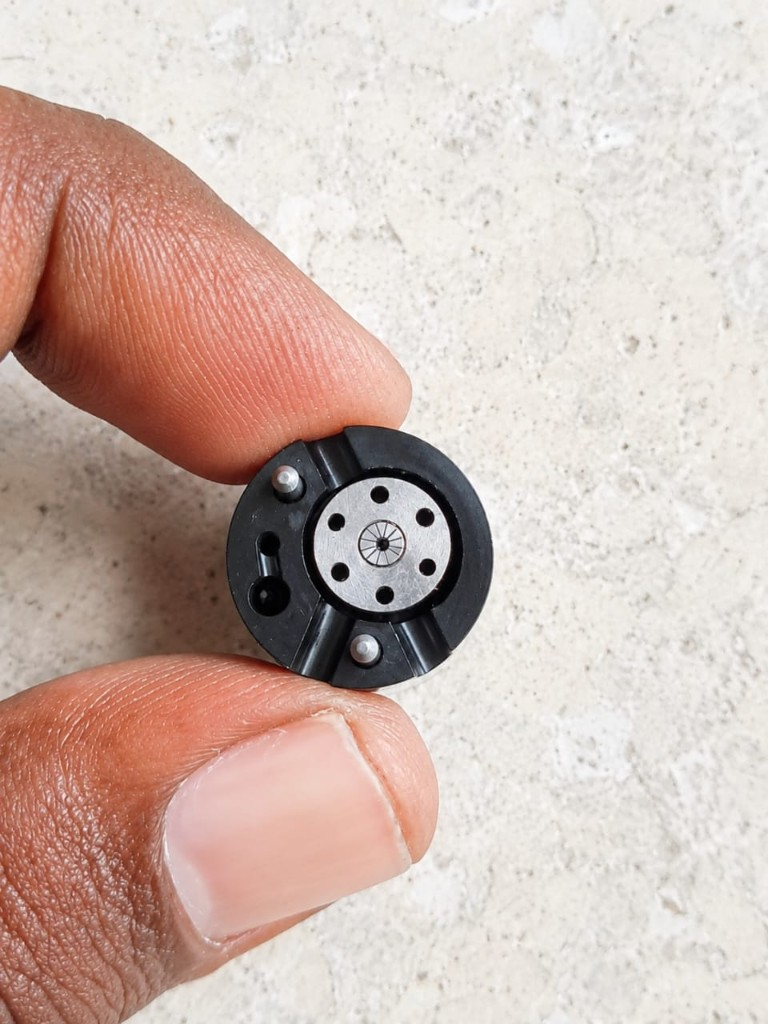 Delphi 28653428 common rail injector control valve top view pins and internal holes held in hand — warehouse photo India export