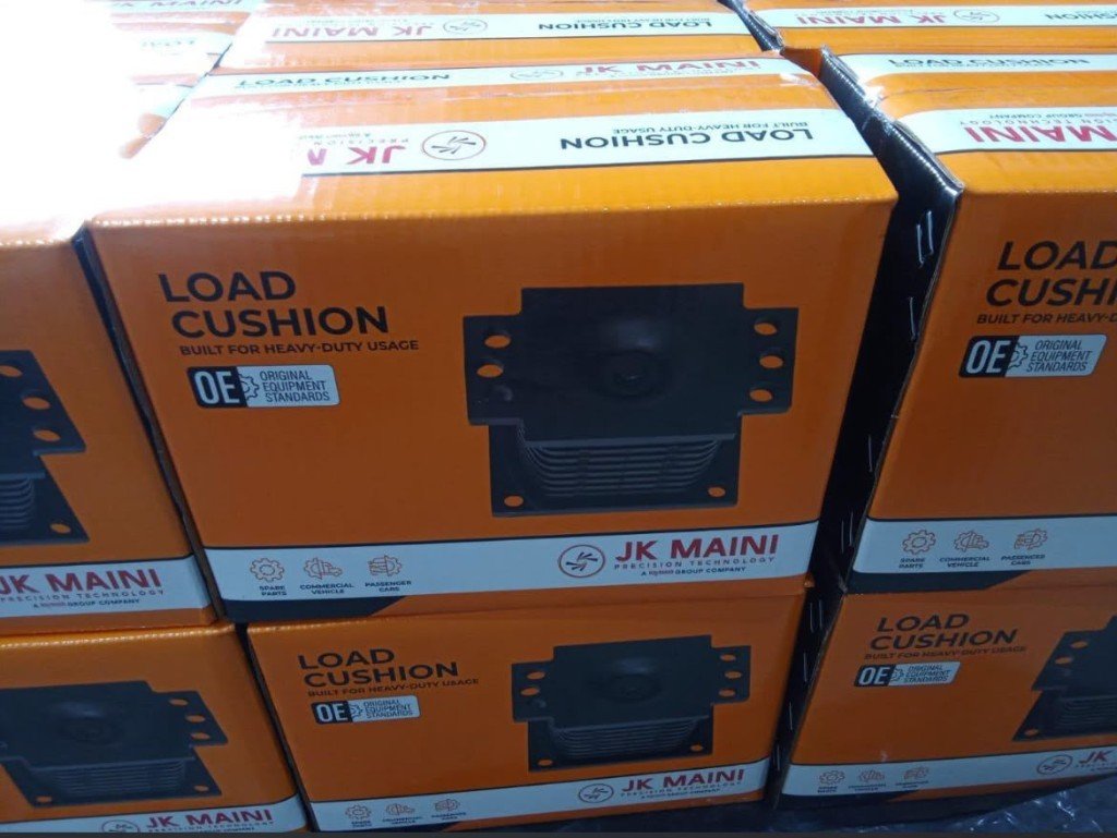 Stacked JK Maini Load Cushion retail boxes in India sourcing warehouse — OE standard heavy-duty commercial and passenger vehicle spare parts — Pioneer Mitra wholesale export