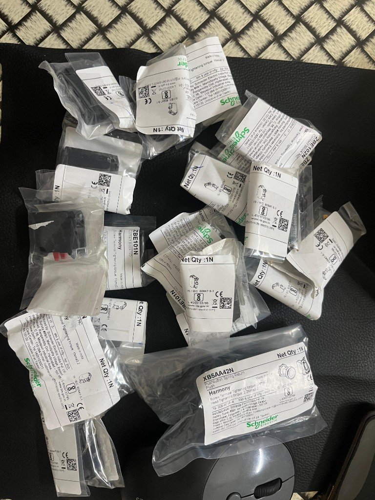 Bulk warehouse pile of packaged Schneider contact blocks and XB5AA42N push buttons — export stock India