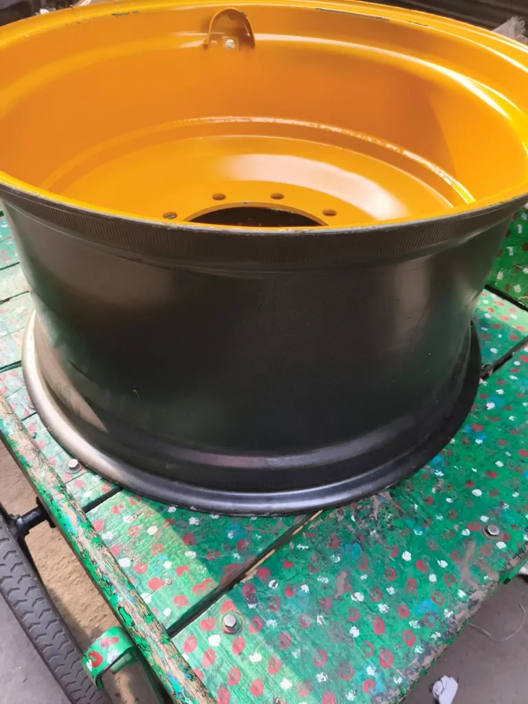 Yellow and black dual-tone industrial wheel rim side profile — heavy-duty backhoe loader class warehouse photo