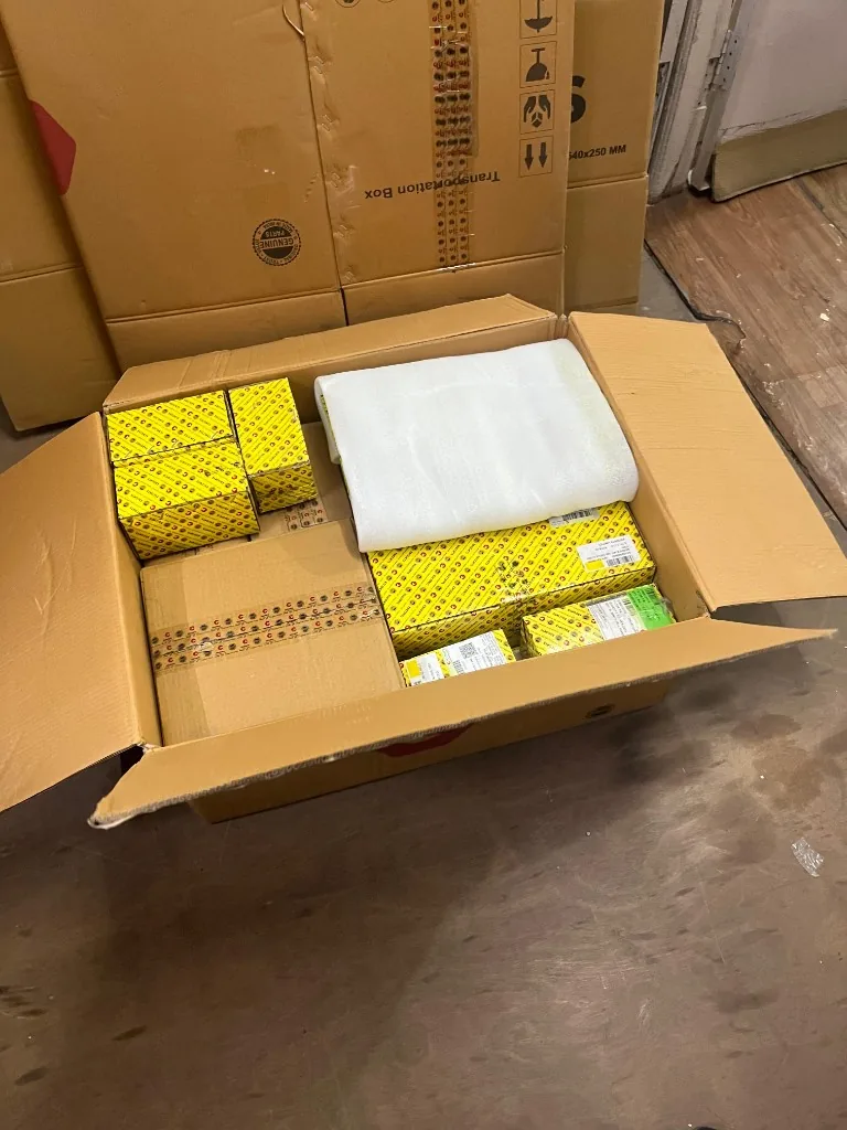 Escorts Kubota open export carton with yellow Genuine Parts boxes and foam padding — warehouse stock photo
