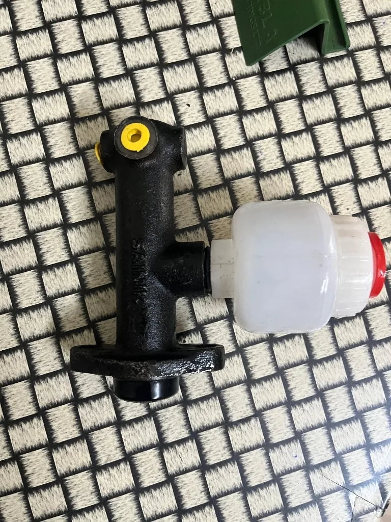 Forklift hydraulic brake master — warehouse photo (embossed body, yellow port caps)