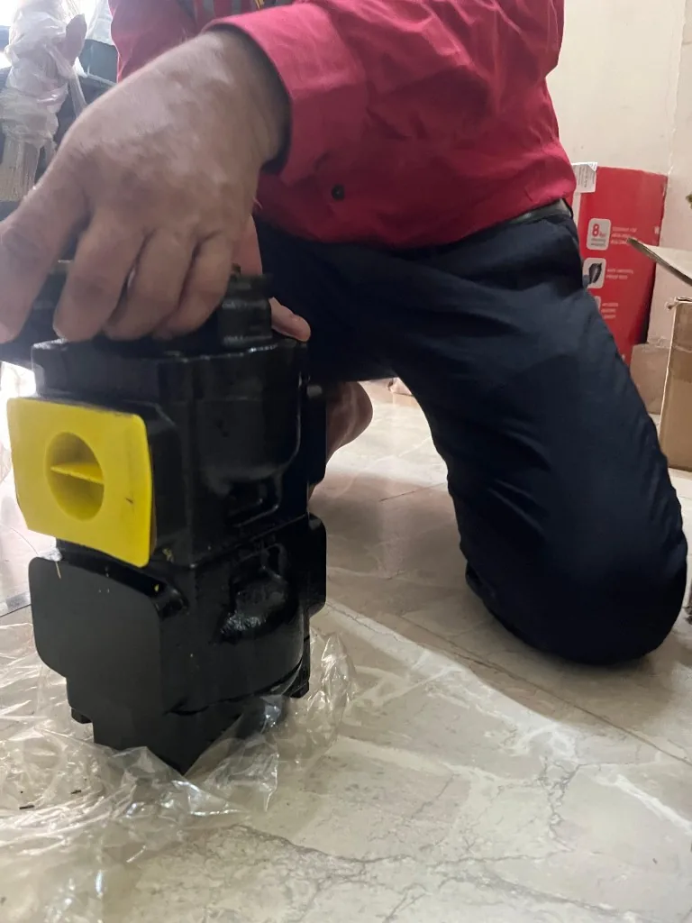 Parker 1002292907 hydraulic pump side angle — yellow port cap visible warehouse export stock photo