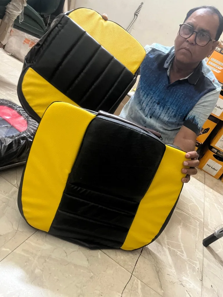 Warehouse staff holding two PU tractor seat covers facing camera — bulk export stock photo