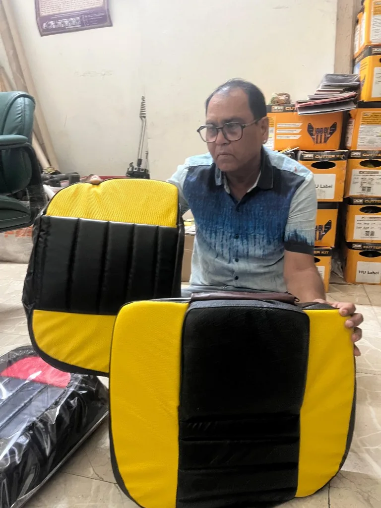 Warehouse staff holding PU tractor seat covers — export stock verification photo India